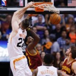 Phoenix Suns' Miles Plumlee, left, dunks over Cleveland Cavaliers' Kyrie Irving (2) as Cavaliers' Spencer Hawes, right, and Suns' Eric Bledsoe (2) look on during the first half of an NBA basketball game on Wednesday, March 12, 2014, in Phoenix. (AP Photo/Ross D. Franklin)