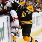 Boston Bruins' Jordan Caron checks Phoenix Coyotes' Rob Klinkhammer into the boards during the third period of Boston's 2-1 win in an NHL hockey game in Boston Thursday, March 13, 2014. (AP Photo/Winslow Townson)