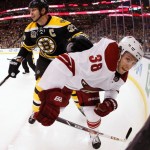 In this photo taken with a fish eye lens, Boston Bruins defenseman Zdeno Chara of Slovakia shoves Phoenix Coyotes' Brandon McMillan (38) into the boards during the third period of Boston's 2-1 win in an NHL hockey game in Boston Thursday, March 13, 2014. (AP Photo/Winslow Townson)