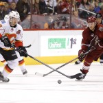Calgary Flames' Curtis Glencross, left, and Phoenix Coyotes' Jeff Halpern chase down the puck during the first period of an NHL hockey game on Saturday, March 15, 2014, in Glendale, Ariz. (AP Photo/Matt York)