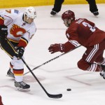 Calgary Flames' Lance Bouma (17) and Phoenix Coyotes' Keith Yandle (3) battle for the puck during the second period of an NHL hockey game, Saturday, March 15, 2014, in Glendale, Ariz. (AP Photo/Matt York)