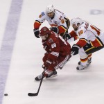 Calgary Flames' Mark Giordano (5) and Brian McGrattan (16) chase down Phoenix Coyotes' Mikkel Boedker (89) for the puck during the second period of an NHL hockey game on Saturday, March 15, 2014, in Glendale, Ariz. (AP Photo/Matt York)