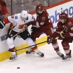Calgary Flames' Ladislav Smid (3) and Phoenix Coyotes' Brandon Gormley (38) and Shane Doan (19) chase down the puck during the second period of NHL hockey game, Saturday, March 15, 2014, in Glendale, Ariz. (AP Photo/Matt York)