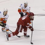 Calgary Flames' T.J. Galiardi (39) and T.J. Brodie (7) defends as Phoenix Coyotes' Shane Doan shoots on goal during the third period of NHL hockey game, Saturday, March 15, 2014, in Glendale, Ariz. The Coyotes won 3-2. (AP Photo/Matt York)