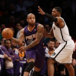 Phoenix Suns' P.J. Tucker, left, passes around Brooklyn Nets's Joe Johnson during the first half of the NBA basketball game at the Barclays Center Monday, March 17, 2014 in New York. (AP Photo/Seth Wenig)