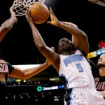 Orlando Magic guard Victor Oladipo (5) shoots betweeb Phoenix Suns center Miles Plumlee, right, and guard Eric Bledsoe during the first half of an NBA basketball game, Wednesday, March 19, 2014, in Phoenix. (AP Photo/Matt York)