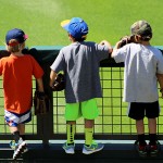 Three young fans eagerly wait on the wall of the outfield lawn in hopes of getting a souvenir. Photo by Zachary Holland/Cronkite News