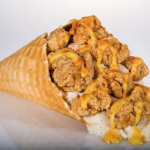 A waffle cone filled with chicken, mashed potatoes and honey mustard drizzle.