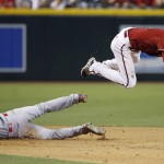 Arizona Diamondbacks' Nick Ahmed, right, leaps over Los Angeles Angels' Taylor Featherston (8) at second base after forcing the runner out and throwing to first base to get Angels' Kyle Kubitza for a double play during the ninth inning of a baseball game Wednesday, June 17, 2015, in Phoenix. The Diamondbacks defeated the Angels 3-2. (AP Photo/Ross D. Franklin)