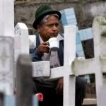 A man drinks the traditional beverage "colada morada" on a relative's grave during Day of the Dead celebrations at the Calderon cemetery in Quito, Friday, Nov. 2, 2007. Residents celebrate Day of the Dead to honor the deceased, a tradition which coincides with All Saints Day and All Souls Day celebrated on Nov. 1 and 2. (AP Photo/Dolores Ochoa)
