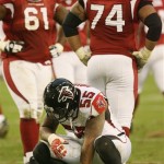 Atlanta Falcons' John Abraham (55) squats on the field after being flagged for a penalty for being offside as Arizona Cardinals' Elton Brown (61) and Reggie Wells (74) wait for the referee to make the call prior to the Cardinals' game-tying field goal in the fourth quarter of an NFL football game Sunday, Dec. 23, 2007, in Glendale, Ariz. The Cardinals defeated the Falcons 30-27 in overtime. (AP Photo/Ross D. Franklin)