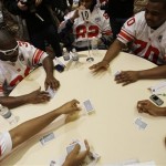 New York Giants' Kay-Jay Harris, left, Brandon London, center, and Na'Shan Goddard, right, take cards dealt by Marcus Freeman during a game of spades while waiting to be interviewed at a player availability session with the media Wednesday, Jan. 30, 2008 in Chandler, Ariz. T=The Giants play the New England Patriots in Super Bowl XLII on Sunday, Feb. 3 in Glendale, Ariz. (AP Photo/Julie Jacobson)
