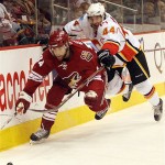 Calgary Flames' Rhett Warrener, right, and Phoenix Coyotes' Daniel Winnik chase down a loose puck during the second period of an NHL hockey game Tuesday, Feb. 19, 2008, in Glendale, Ariz. (AP Photo/Roy Dabner)