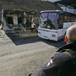 A Polish KFOR police officer watches a Kosovo Serb bus crossing through a United Nations checkpoint, recently demolished and burnt by angry Kosovo Serbs, in the village of Jarinje, on the Serbia-Kosovo border, Thursday, Feb. 21, 2008. Thousands of angry Serbs were converging on Belgrade Thursday to attend a rally to protest against Kosovo's declaration of independence. (AP Photo/Srdjan Ilic)