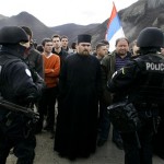 A Serb Orthodox priest stands behind Polish soldiers serving in KFOR, as NATO peacekeeping forces temporarily closed the checkpoint of Jarinje, on the border between Serbia and Kosovo, Friday, Feb.22, 2008. KFOR forces prevented buses with citizens from Serbia from joining a student demonstration in Kosovska Mitrovica, in fear that the Serbian hooligans, the same ones who attacked the U.S. and other embassies in Belgrade on Thursday, were among those on the buses. Some of Serbs protesting Kosovo's independence attacked U.N. police guarding a key bridge over Ibar river in northern Serb dominated ethnically divided town of Kosovska Mitrovica, with stones and empty glass bottles. (AP Photo/Srdjan Ilic)
