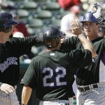 Colorado Rockies' Brad Hawpe, right, is congratulated by Todd Helton, and Marcus Giles after scoring the trio on his three run home run during the first inning of a spring training baseball game Against the Arizona Diamondbacks Monday, in Tucson, Ariz. The Rockies defeated the Diamondbacks 7-5.