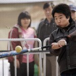 A Chinese boy swings at a ball in a Major League Baseball-sponsored batting cage at Wukesong Baseball Stadium during a game between the Los Angeles Dodgers and the San Diego Padres, Sunday, March 16, 2008, in Beijing, China. (AP Photo/Robert F. Bukaty)