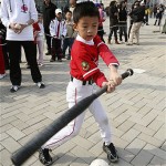 A young baseball player takes a swing a ball on a tee at an Major League Baseball-sponsored exhibition at Wukesong Baseball Stadium during a game between the Los Angeles Dodgers and the San Diego Padres, Sunday, March 16, 2008, in Beijing, China. (AP Photo/Robert F. Bukaty)