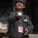 A Chinese security guard plays with a baseball after it was hit over the leftfield fence at Wukesong Baseball Field during the San Diego Padres' batting practice before an exhibition game against the Los Angeles Dodgers, Sunday, March 16, 2008, in Beijing, China. (AP Photo/Robert F. Bukaty)