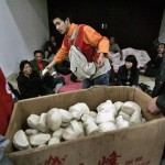 Volunteers distribute bread to the earthquake victims inside a stadium, which was converted to a temporary shelter following Monday's powerful 7.9 magnitude earthquake in Mianyang, Sichuan province, China, Tuesday, May 13, 2008. Rescue workers sifted through tangled debris of toppled schools and homes Tuesday for thousands of victims buried or missing after China's worst earthquake in three decades, as the death toll soared to more than 12,000 people in the hardest-hit province alone. (AP Photo /Andy Wong)