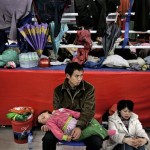 A Chinese couple with their child inside a stadium, which was converted to a temporary shelter following Monday's powerful 7.9 magnitude earthquake in Mianyang, Sichuan province, China, Tuesday, May 13, 2008. Rescue workers sifted through tangled debris of toppled schools and homes Tuesday for thousands of victims buried or missing after China's worst earthquake in three decades, as the death toll soared to more than 12,000 people in the hardest-hit province alone. (AP Photo /Andy Wong)