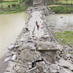 People walk on a bridge collapsed following Monday's powerful 7.9 magnitude earthquake in Mianyang, southwest China's Sichuan Province, Tuesday, May 13, 2008. Chinese rescue workers have reported that 3,629 people had been confirmed dead and 18,645 were still buried under debris in the city, which neighbors the epicenter of the massive earthquake that struck China. (AP Photo/Kyodo News)