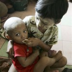 A Myanmar boy feeds a banana to his younger brother at a temple being used a temporary shelter for cyclone survivors on the outskirts of Yangon, Myanmar, Tuesday, May 13, 2008. (AP Photo)