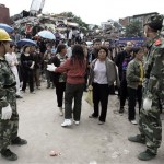 While guarded by Chinese paramilitary police, onlookers watch rescue workers search for survivors at a collapsed school following Monday's powerful 7.9 magnitude earthquake in Hanwang town in Sichuan province, China, Wednesday, May 14, 2008.