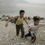 Earthquake survivors climb up a rocky embankment after arriving on a boat from areas inaccessible by road at the Zipingpu Dam near Dujiangyan, southwestern China's Sichuan province, Friday, May 16, 2008. China warned the death toll from this week's earthquake could soar to 50,000, while the government issued a rare public appeal Thursday for rescue equipment as it struggled to cope with the disaster. (AP Photo/Vincent Yu)