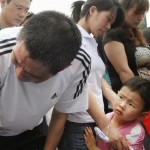 A child looks at a crying man as the survivors mourn for the earthquake victims in Chengdu, China's southwest Sichuan Province Tuesday, May 20, 2008. China said it was struggling to find shelter for many of the 5 million people whose homes were destroyed in last week's earthquake, while the confirmed death toll rose Tuesday to more than 40,000. (AP Photo/Kyodo News)