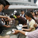 Quake survivors receive rice porridge on ration outside a gymnasium they take shelter, in Mianyang, China's southwest Sichuan Province Tuesday, May 20, 2008. China said it was struggling to find shelter for many of the 5 million people whose homes were destroyed in last week's earthquake, while the confirmed death toll rose Tuesday to more than 40,000. (AP Photo/Kyodo News)