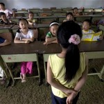 Young Chinese quake survivors take part in singing lessons inside a temporary classroom set up for children affected by last week's earthquake in Chengdu, southwestern China's Sichuan province, Tuesday, May 20, 2008. China said it was struggling to find shelter for many of the 5 million people whose homes were destroyed in last week's earthquake, while the confirmed death toll rose Tuesday to more than 40,000. (AP Photo/Ng Han Guan)
