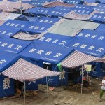 A woman walks past a tent community near Yongan, southwest China's Sichuan province, Friday, June 13, 2008. One month after a magnitude-7.9 quake killed nearly 70,000 in central China, Beijing is trying to switch the emphasis from the destruction to the rebuilding effort, focusing on tales of heroism in the rescue efforts. (AP Photo/Ng Han Guan)
