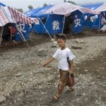 A child carrying a toy rifle walks past tents at a tent community near Yongan, southwest China's Sichuan province, Friday, June 13, 2008. One month after the magnitude-7.9 quake killed nearly 70,000 in central China, Beijing is trying to switch the emphasis from the destruction to the rebuilding effort, focusing on tales of heroism in the rescue efforts. (AP Photo/Ng Han Guan)