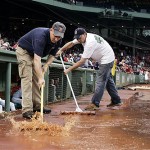 Grounds crew squeegee excess water from the front of the Boston Red Sox dugout after a rainstorm delayed the start of the baseball game between the Red Sox and the Arizona Diamondbacks at Fenway Park in Boston Tuesday.