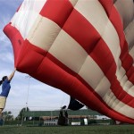 Ground crew member Sally Mazzocchi holds on as she tries to steady a 53-foot-tall American Flag hot air balloon in the wind as it is inflated at Dobbelaar baseball field Thursday, July 3, 2008, in Hoboken, N.J. (AP Photo/Mel Evans)
