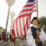 Hannah Wernher holds the 13-star, American flag, as the Mountain Fife & Drums from lake Arrowhead, Calif., warm up in the fog before the annual Fourth of July parade in Huntington Beach, Calif., Friday, July 4, 2008. (AP Photo/Mark Avery)
