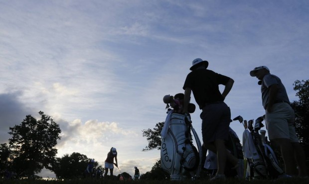 Caddies talk as golfers warm up before play resumed in the first round of the U.S. Women’s Op...