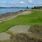
              In this Sept. 30, 2014, file photo, the 16th hole of the Chambers Bay golf course is shown as a freight train passes at left in University Place, Wash. Next week the course, which opened in 2007, will become the youngest golf course to host the U.S. Open since Hazeltine in 1970. (AP Photo/Ted S. Warren, file)
            
