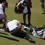 
              Jason Day, of Australia, lies in the fairway after falling down as his caddie Colin Swatton crouches beside him on the ninth hole during the second round of the U.S. Open golf tournament at Chambers Bay on Friday, June 19, 2015 in University Place, Wash. (AP Photo/Ted S. Warren)
            