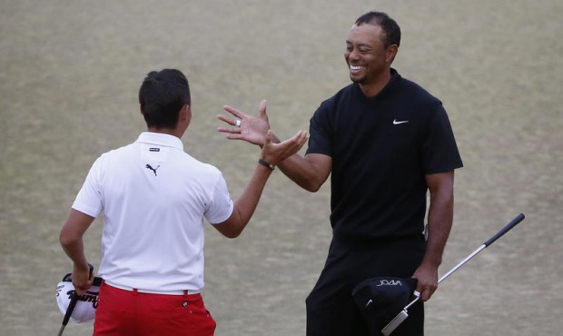 Tiger Woods, right, and Rickie Fowler shake hands after the first round of the U.S. Open golf tourn...
