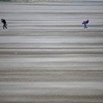 
              People walk on a windswept beach near the course as high winds suspend play during the second round of the British Open Golf Championship at the Old Course, St. Andrews, Scotland, Saturday, July 18, 2015. (AP Photo/Jon Super)
            