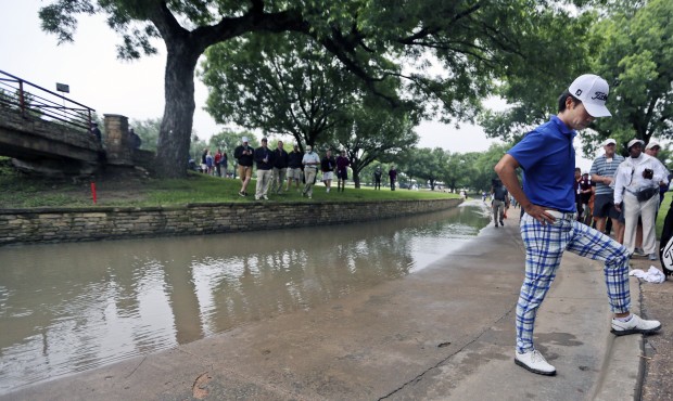 Kevin Na looks at the spot his ball landed before bouncing into a rain-swollen drainage culvert adj...