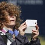 
              The hair of a spectator is blown over her face as she tries to take her photo after play was suspended due to high winds during the second round of the British Open Golf Championship at the Old Course, St. Andrews, Scotland, Saturday, July 18, 2015. (AP Photo/Jon Super)
            