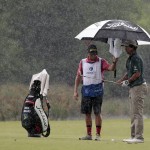
              Mark Hubbard's caddie holds an umbrella over him while he prepares for his chip shot on the 18th hole during the first round of the Zurich Classic PGA golf tournament, Thursday, April 23, 2015, in Avondale, La. (AP Photo/Butch Dill)
            