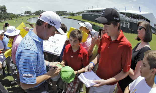 Jimmy Walker, left, signs autographs for fans as he comes off the 18th green during a practice roun...