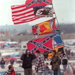 
              FILE - In this April 26, 1997, file photo, race fans huddle against a bitter wind at the Talladega Superspeedway  during the rain-delayed NASCAR Busch series auto race in Talladega, Ala. NASCAR  backed South Carolina Gov. Nikki Haley's call this week to remove the Confederate flag from the Statehouse grounds in the wake of the Charleston church massacre. Though NASCAR now bars the use of the flag in any "official capacity," they are as easy to find at NASCAR races as cutoff jeans, cowboy hats, and beer. (AP Photo/Dave Martin, File)
            