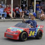 
              A fan waves as he  drives a replica of NASCAR driver Jeff Gordon's car in front of fans that lines the route of a parade to honor Gordon in Pittsboro, Ind., Thursday, July 23, 2015. Gordon will drive in Sunday's Brickyard 400.  (AP Photo/Michael Conroy)
            