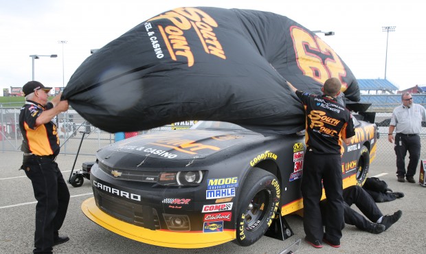 The crew for the Brendan Gaughan’s car work to get the car covered as rain starts to fall bef...