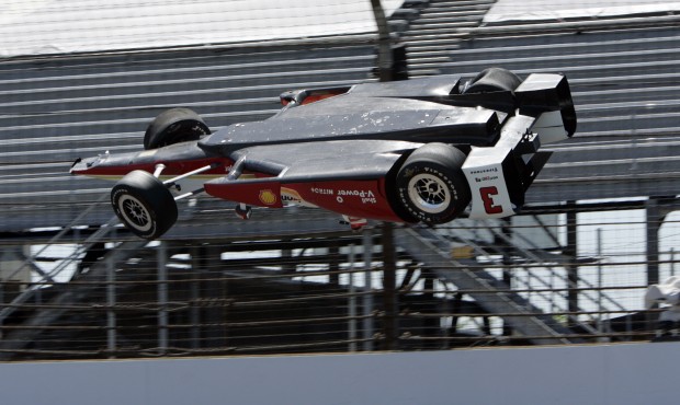 The car driven by Helio Castroneves, of Brazil, is airborne after hitting the wall in the first tur...
